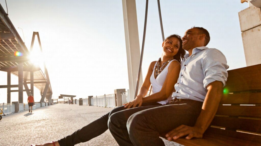 2 people sitting and smiling on a swing at the waterfront park