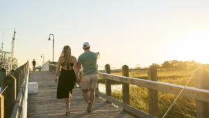 A couple walking together holding hands at Shem Creek