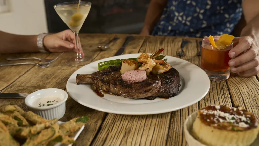 A steak on a table with people having drinks