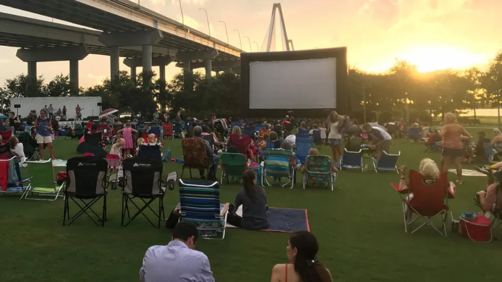 A large group of people sitting and watching an outdoor movie